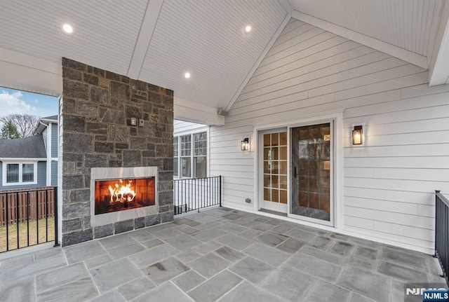 view of patio featuring an outdoor stone fireplace and fence