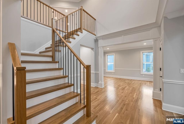 stairway featuring a high ceiling, wood finished floors, and baseboards