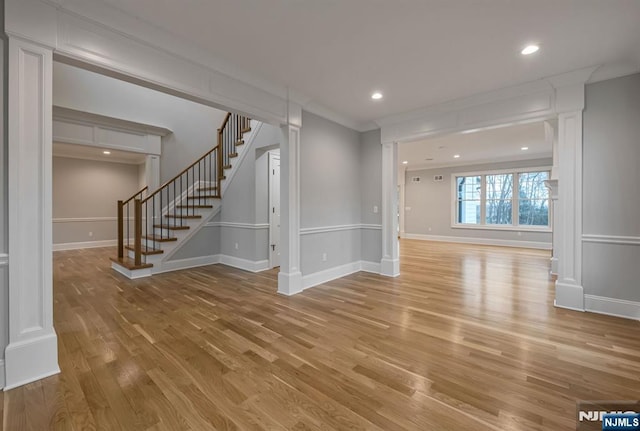 spare room with baseboards, ornamental molding, stairs, light wood-style floors, and recessed lighting