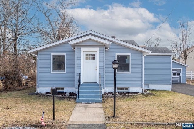 bungalow-style house featuring entry steps, a front lawn, and roof with shingles