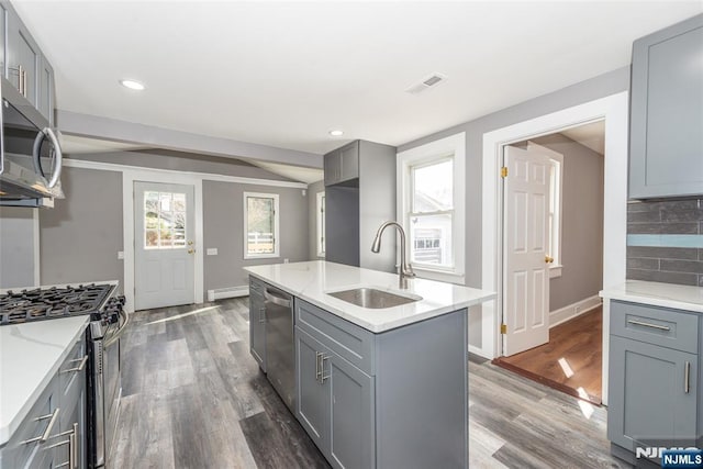 kitchen featuring a sink, stainless steel appliances, baseboard heating, and gray cabinets