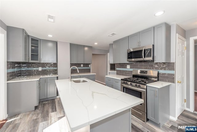 kitchen with appliances with stainless steel finishes, a sink, and gray cabinetry