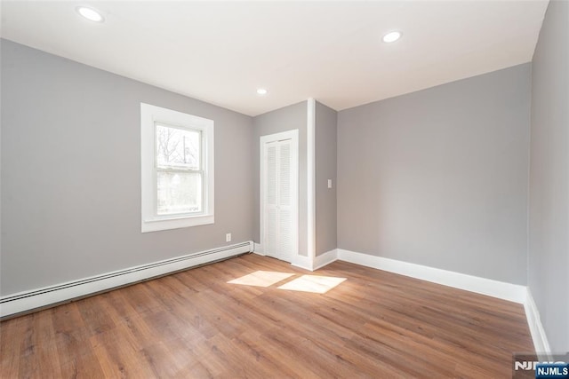 spare room with recessed lighting, baseboards, baseboard heating, and wood finished floors