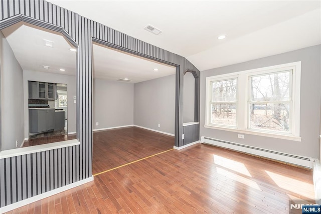 empty room with recessed lighting, wood finished floors, visible vents, baseboards, and baseboard heating