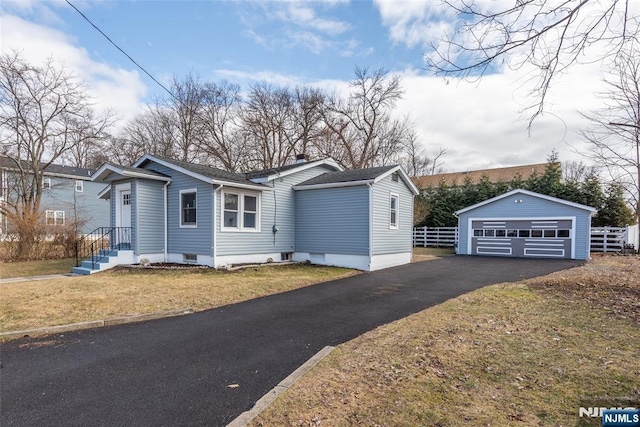 view of front of house with an outdoor structure, fence, a detached garage, and a front yard