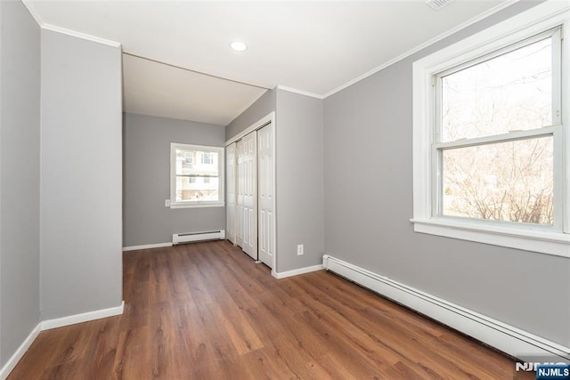 unfurnished bedroom featuring a baseboard radiator, a baseboard heating unit, wood finished floors, baseboards, and ornamental molding