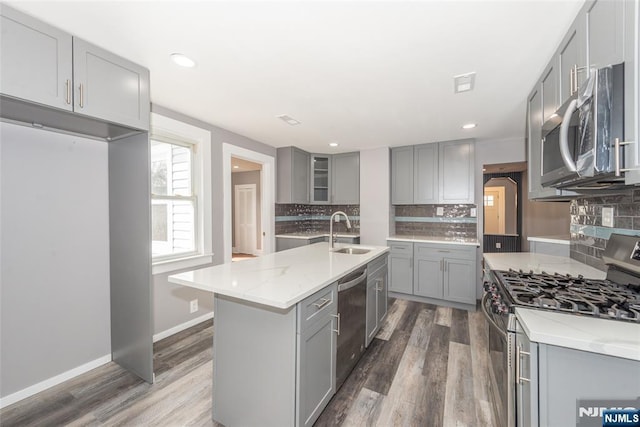 kitchen with stainless steel appliances, a sink, gray cabinetry, and dark wood-style floors