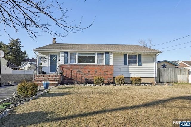 bungalow featuring brick siding, a chimney, a front lawn, and fence