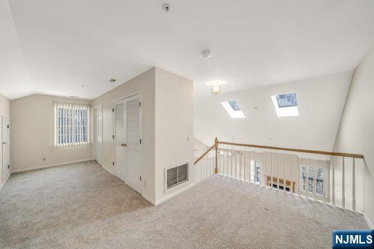 bonus room featuring visible vents, lofted ceiling with skylight, and carpet floors