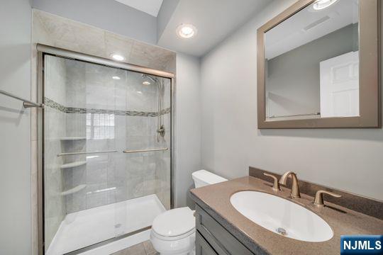 full bath featuring a shower stall, toilet, and vanity