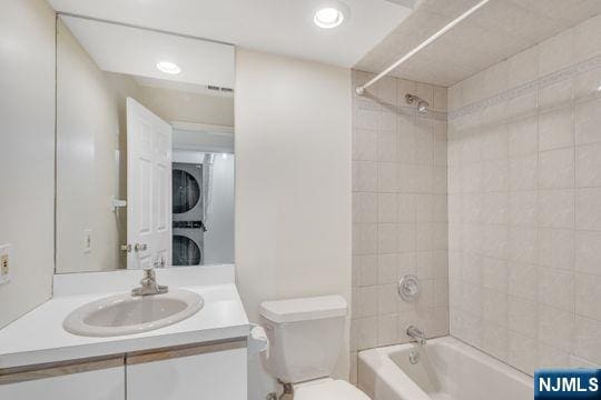 bathroom featuring toilet, stacked washer and dryer, recessed lighting, shower / bathing tub combination, and vanity