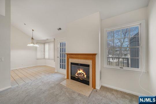 unfurnished living room with visible vents, a fireplace with flush hearth, carpet floors, baseboards, and vaulted ceiling