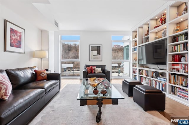 living area featuring plenty of natural light, visible vents, and wood finished floors