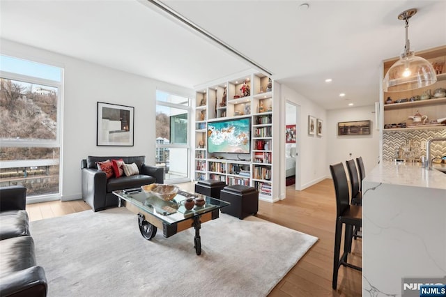 living room with recessed lighting, baseboards, a healthy amount of sunlight, and light wood-style flooring