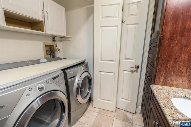 clothes washing area with cabinet space, separate washer and dryer, a sink, and light tile patterned flooring