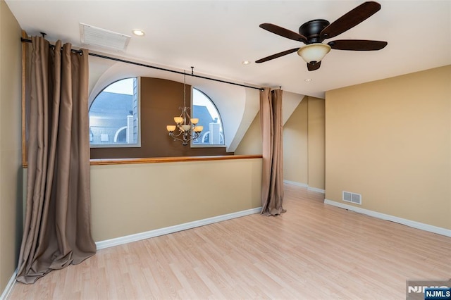 unfurnished room featuring baseboards, visible vents, and wood finished floors