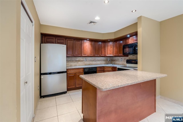 kitchen featuring electric range, visible vents, freestanding refrigerator, black microwave, and a sink