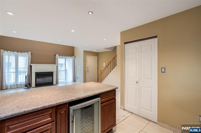 kitchen featuring a fireplace with flush hearth, wine cooler, open floor plan, light tile patterned flooring, and recessed lighting