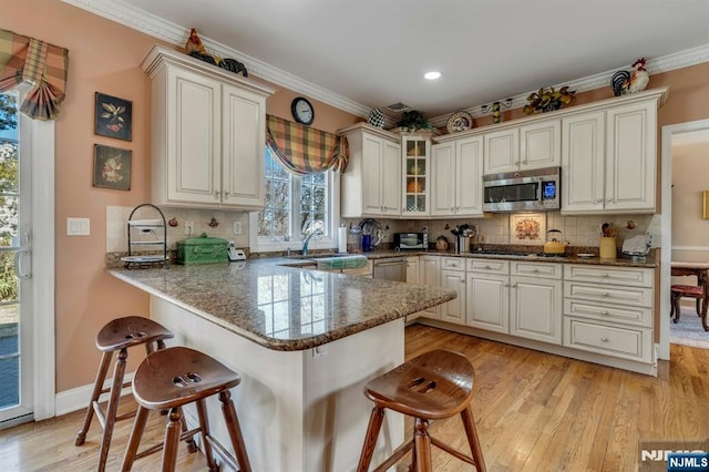 kitchen featuring a kitchen bar, ornamental molding, and stainless steel appliances