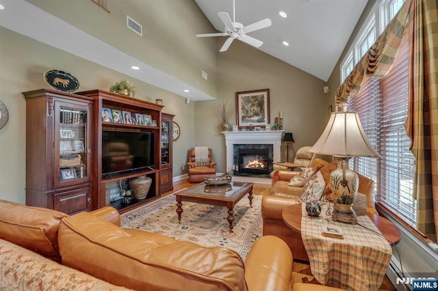 living room with a wealth of natural light, visible vents, baseboard heating, and a high end fireplace