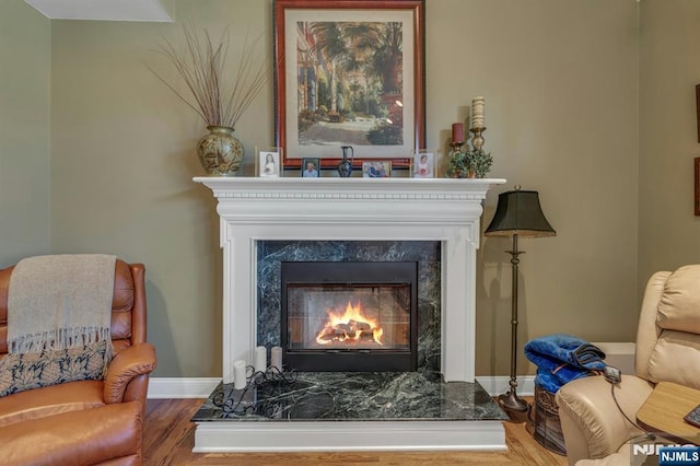 sitting room featuring baseboards, wood finished floors, and a high end fireplace