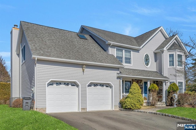 traditional-style home featuring driveway, a chimney, an attached garage, and a shingled roof