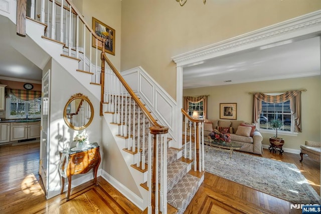 staircase featuring a wealth of natural light, baseboards, and crown molding