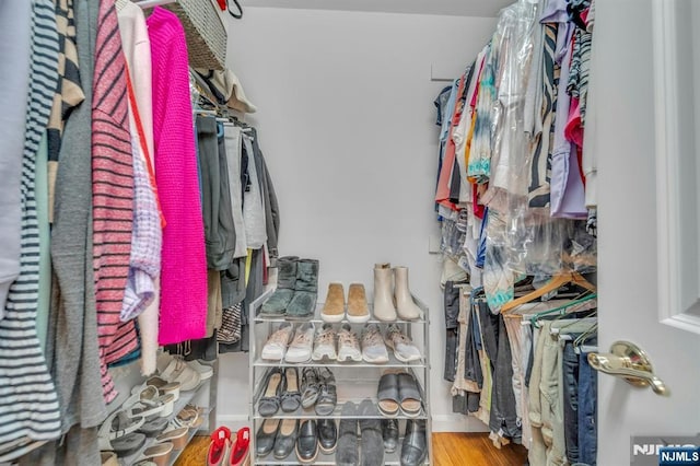 walk in closet with wood finished floors