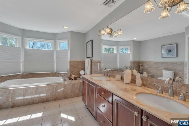 full bathroom featuring tile patterned flooring, visible vents, a garden tub, and a sink