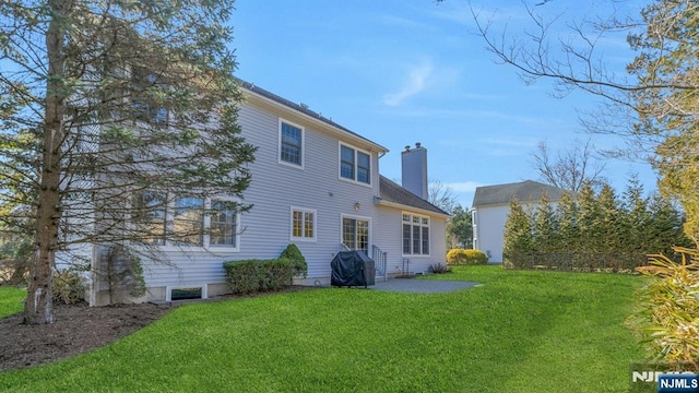 back of house featuring a patio, a lawn, and a chimney