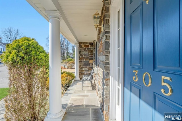 view of exterior entry featuring stone siding and covered porch