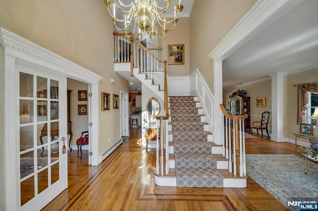 foyer featuring a baseboard heating unit, ornamental molding, stairs, and a chandelier