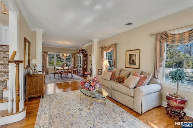 living area with visible vents, plenty of natural light, light wood-style floors, and ornate columns