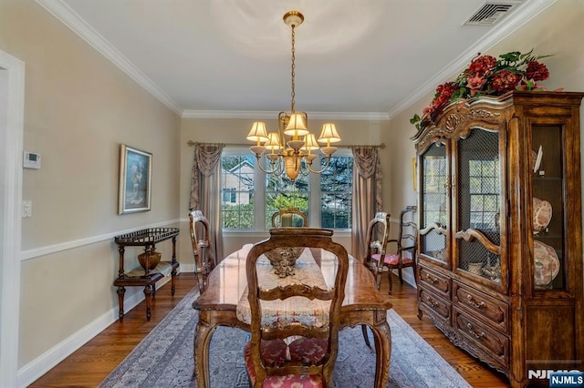 dining room with visible vents, crown molding, baseboards, a chandelier, and wood finished floors