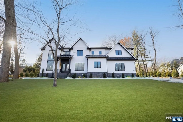 modern farmhouse style home with a front yard, a standing seam roof, and metal roof