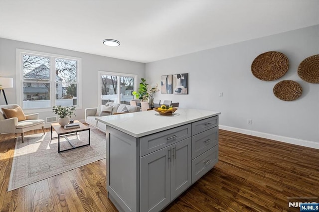 kitchen featuring dark wood-style flooring, visible vents, baseboards, light countertops, and gray cabinets