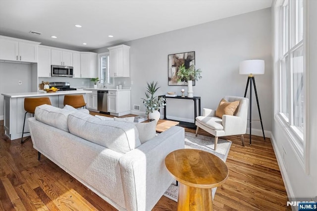 living room featuring baseboards, wood finished floors, visible vents, and recessed lighting