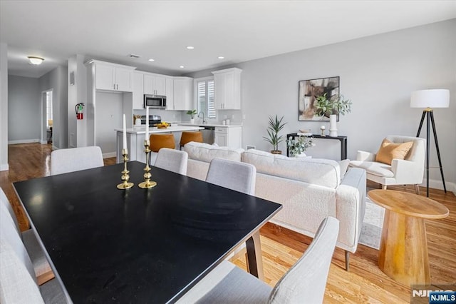 dining area featuring baseboards, light wood-style flooring, and recessed lighting