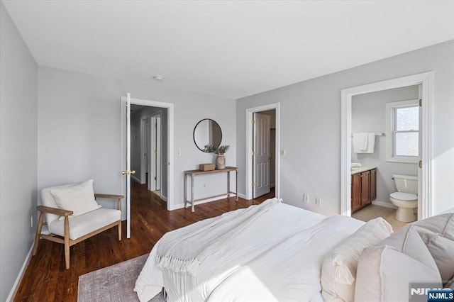 bedroom featuring ensuite bathroom, baseboards, and wood finished floors