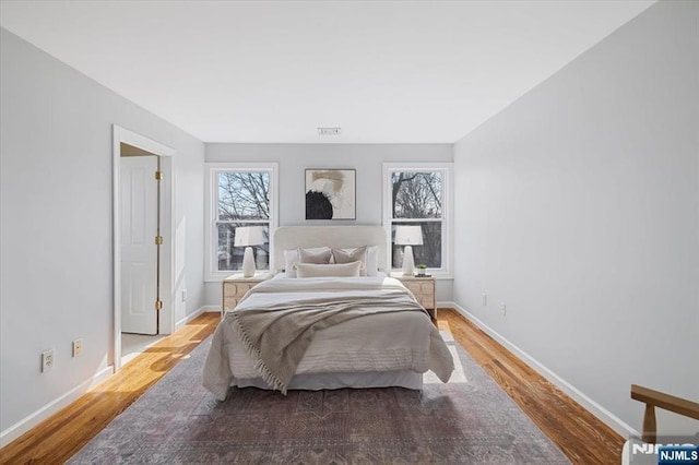 bedroom with visible vents, baseboards, and wood finished floors