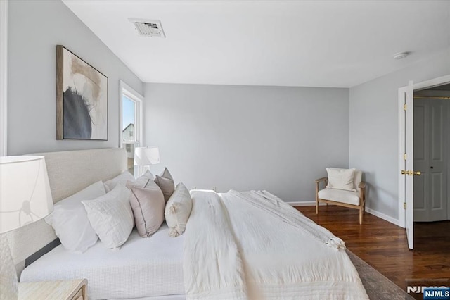 bedroom with dark wood-style floors, visible vents, and baseboards