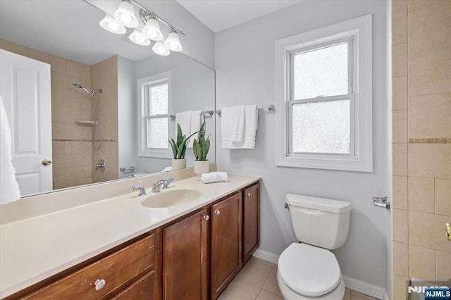 bathroom featuring baseboards, toilet, tile patterned floors, a tile shower, and vanity