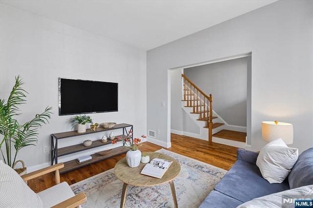 living room with visible vents, stairway, baseboards, and wood finished floors