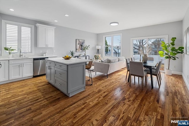 kitchen featuring dishwasher, a kitchen island, dark wood-style flooring, light countertops, and gray cabinetry