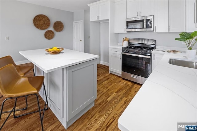 kitchen featuring a center island, a breakfast bar area, appliances with stainless steel finishes, a sink, and wood finished floors