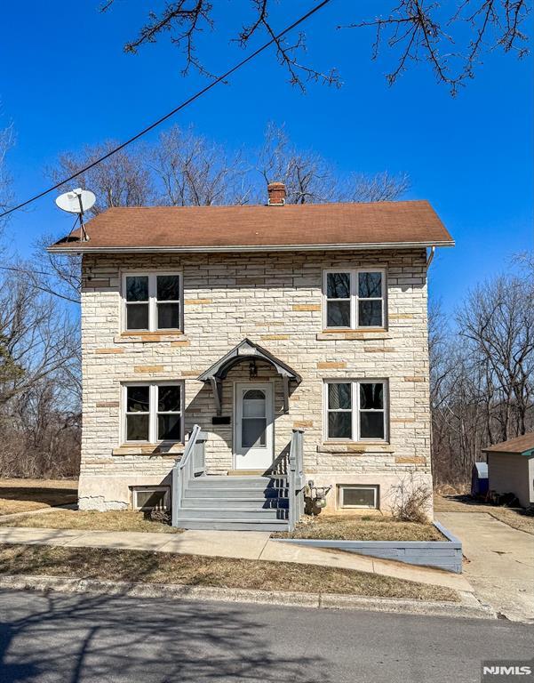 view of front facade with stone siding and a chimney