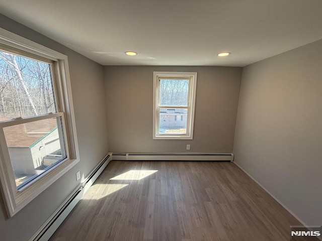 unfurnished room with recessed lighting, baseboard heating, and wood finished floors