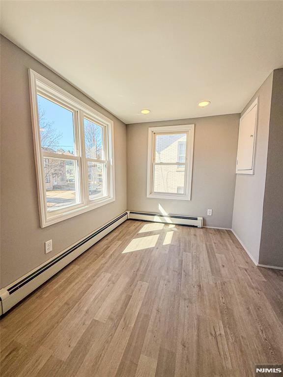 spare room featuring a wealth of natural light, light wood-style flooring, and a baseboard radiator