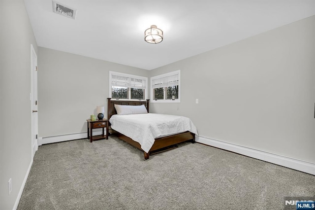 carpeted bedroom featuring visible vents, a baseboard heating unit, and baseboards