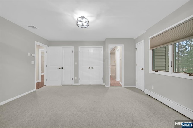 carpeted entrance foyer with a baseboard heating unit, visible vents, and baseboards